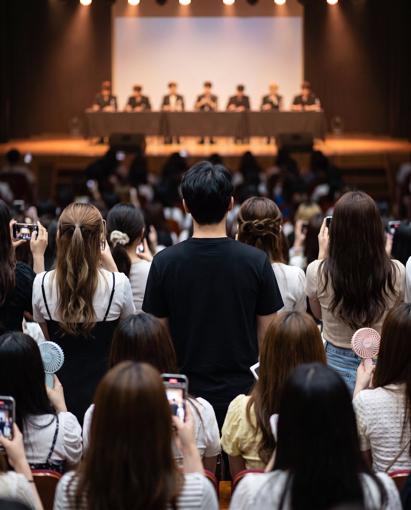 The only man in a crowd of women at a fansign, watching the stage
